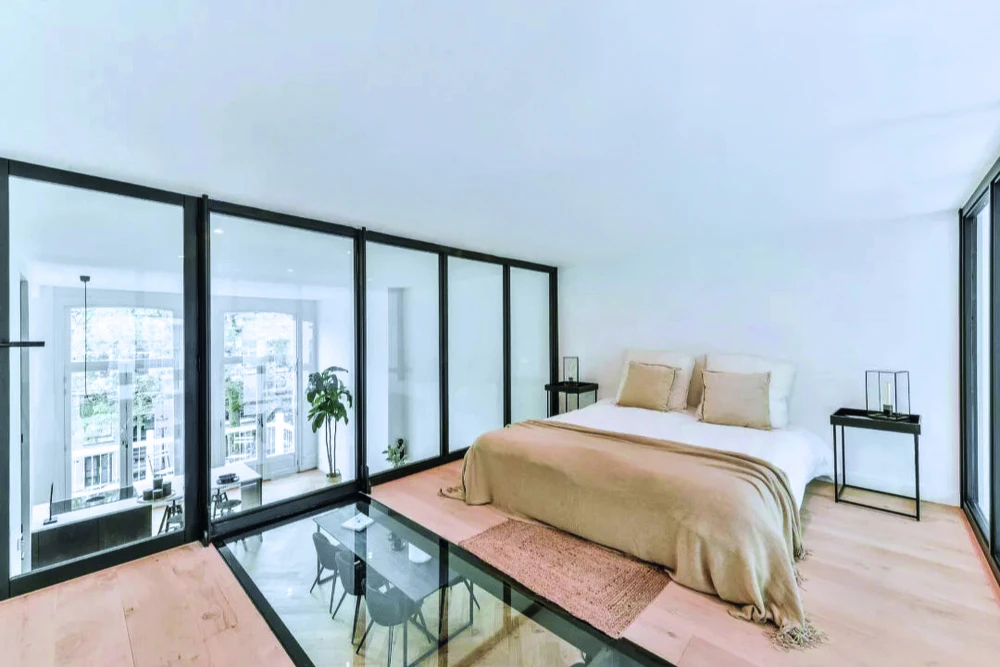 Appartement moderne avec séparation verrière industrielle noire délimitant la chambre du salon