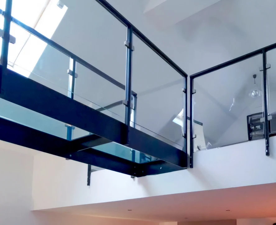 Homme en t-shirt blanc versant de l'eau d'une carafe en verre transparent dans un verre sur table blanche, intérieur lumineux avec fenêtre en arrière-plan