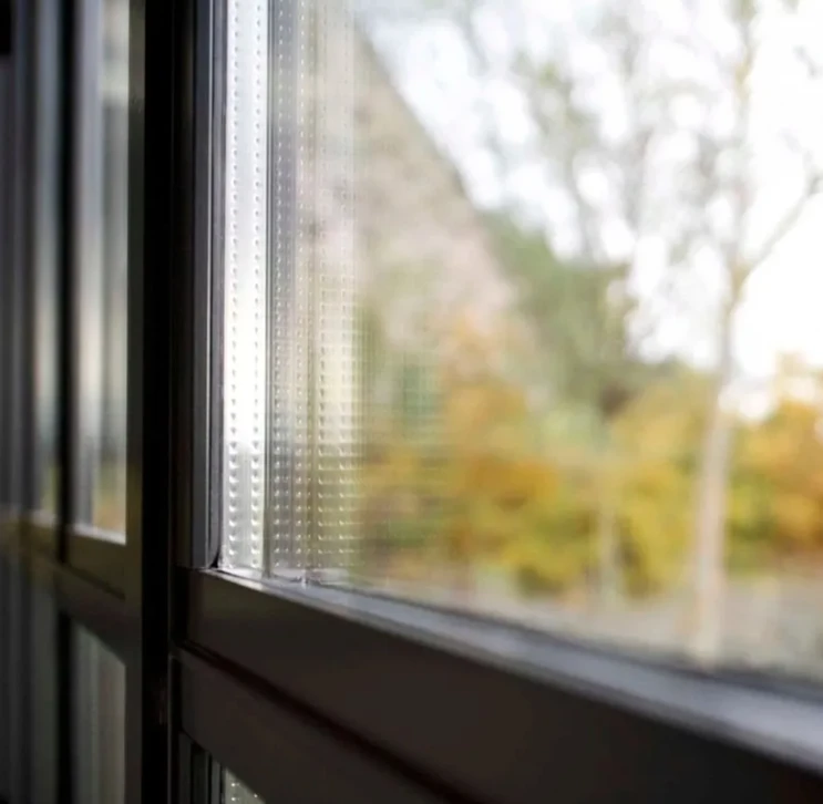 Sc&egrave;ne ext&eacute;rieure avec reflet d'un cycliste et d'un paysage verdoyant sur une surface vitr&eacute;e de v&eacute;hicule